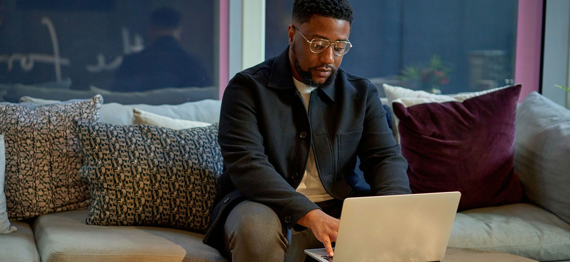 Man seated on couch working on computer