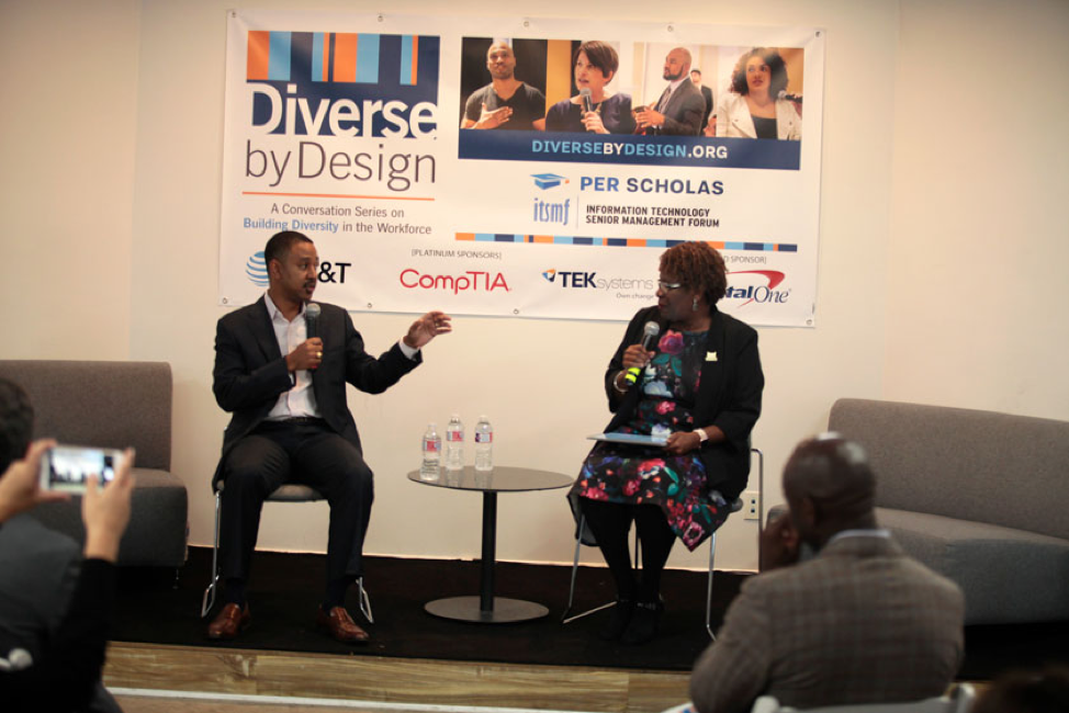 Two panelists sit on stage holding microphones during a Diverse by Design event conversation.
