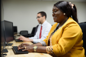 Two adult students working at computers in a classroom.
