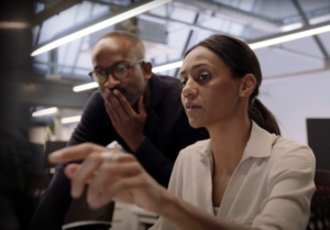 Two coworkers focused on a computer screen while one woman points at the display.