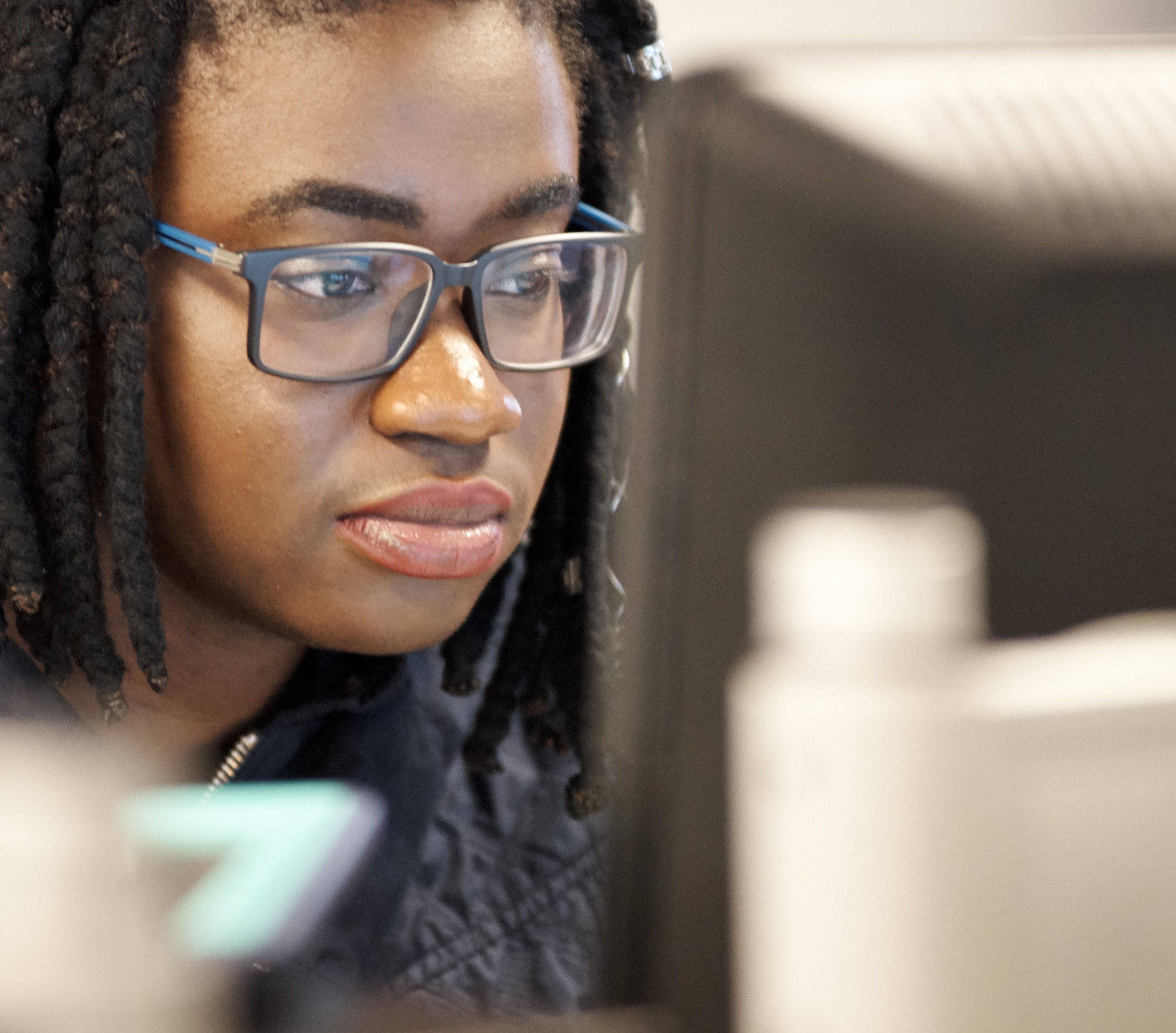 A Per Scholas learner in glasses focused on a computer screen
