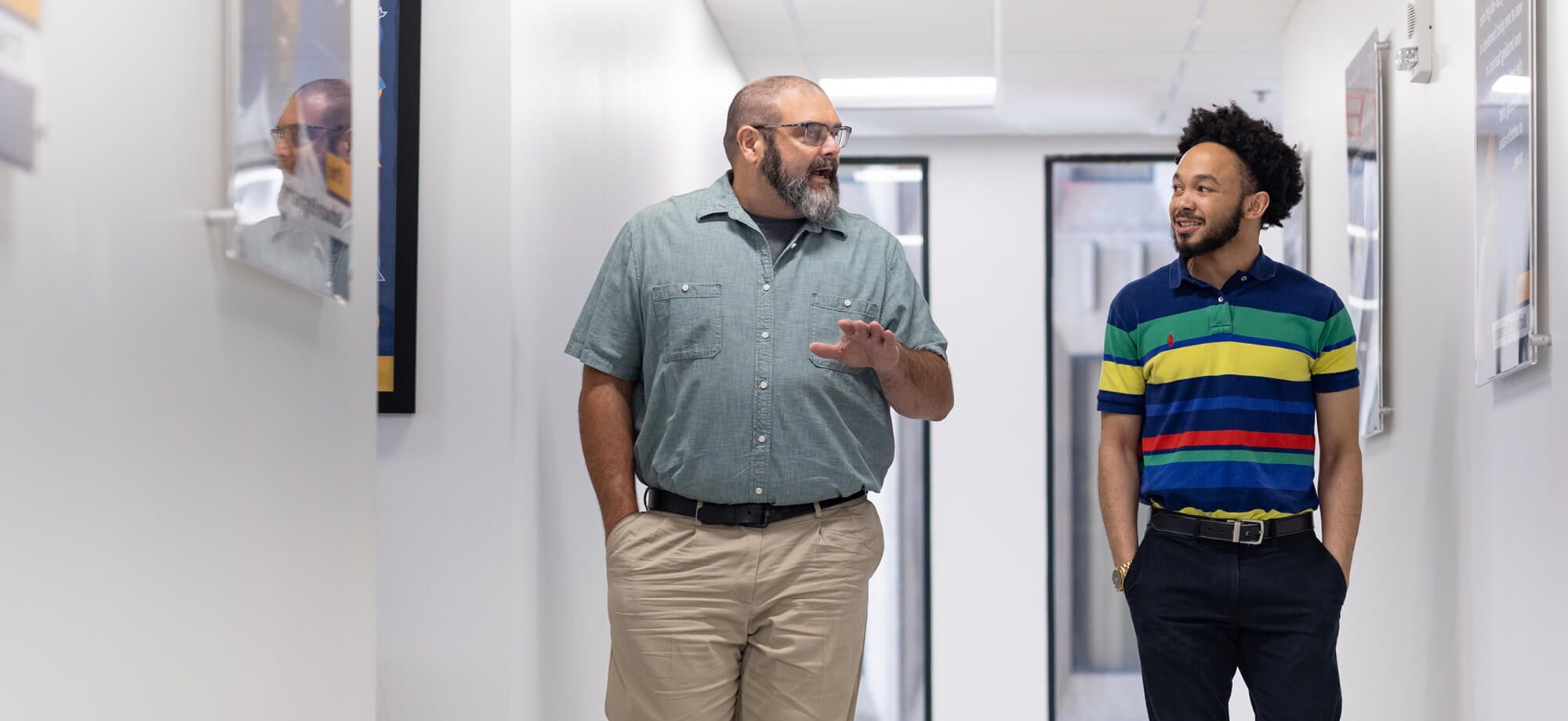 Mentor and student walking down campus hallways