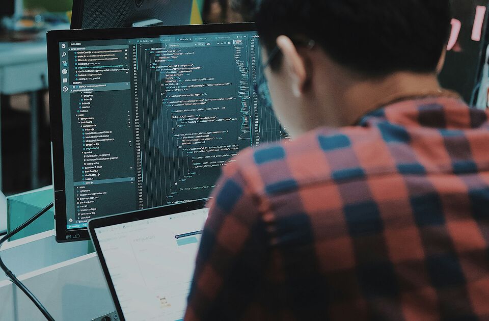 Person working on code displayed across two computer screens.