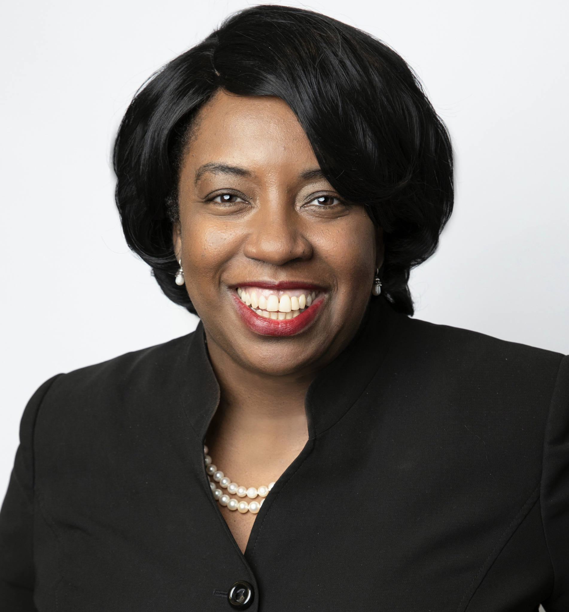 Senta Taylor smiling, wearing a blazer and pearl necklace in a professional headshot.
