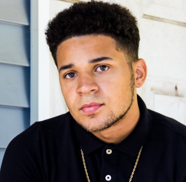 Headshot of Aaron Webb while seated against a porch wall.