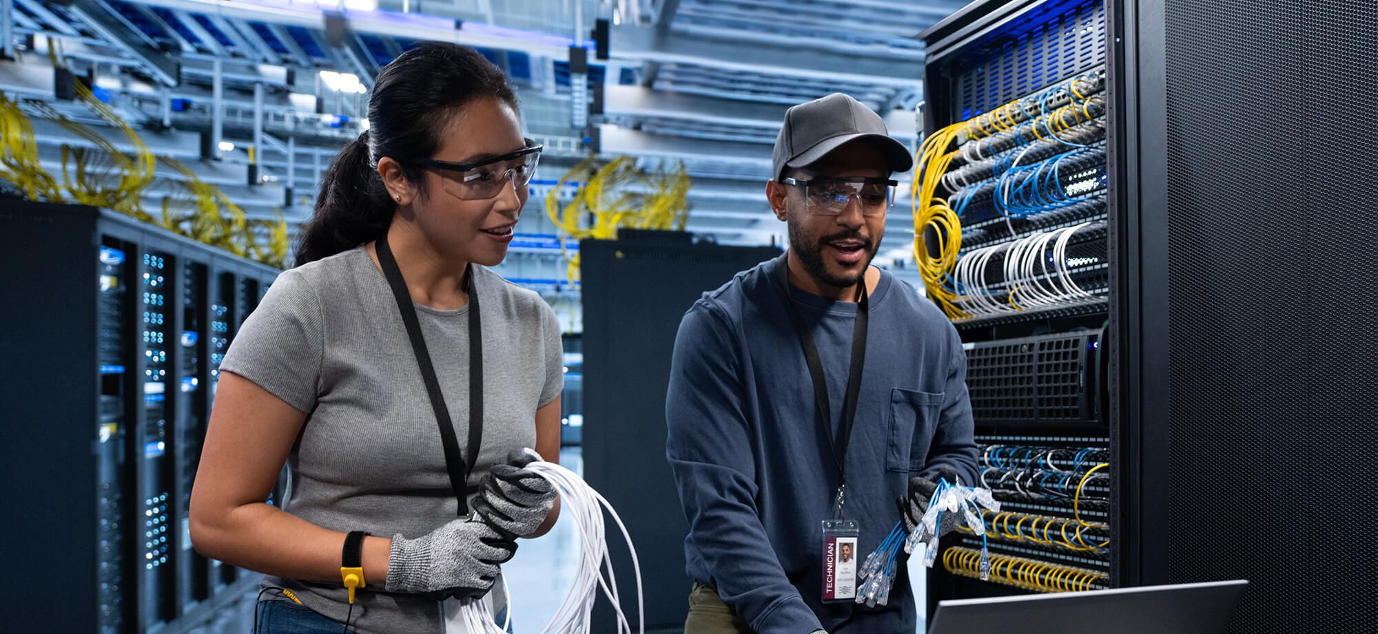 Pair of employees working in data center looking at laptop