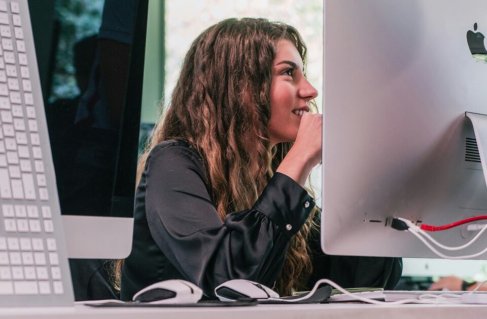 Female student sitting in front of computer screen in classroom.