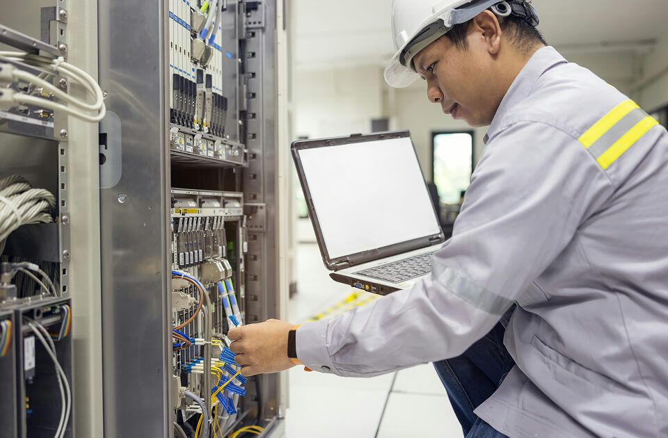 Male technician working with laptop at data center.