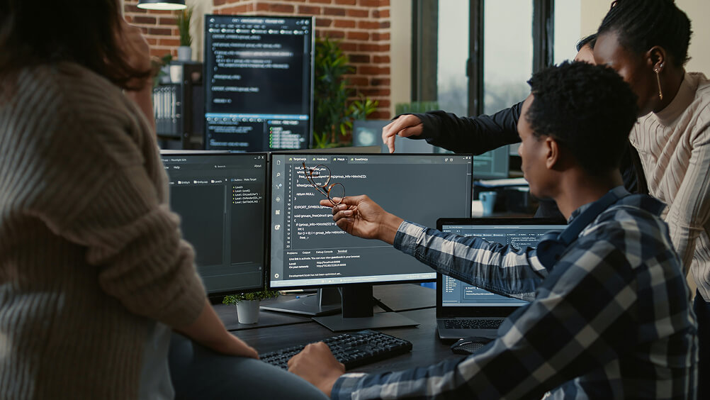 Group of programmers problem solving code at computer
