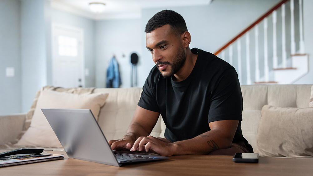 Man in home seated on couch looking at laptop