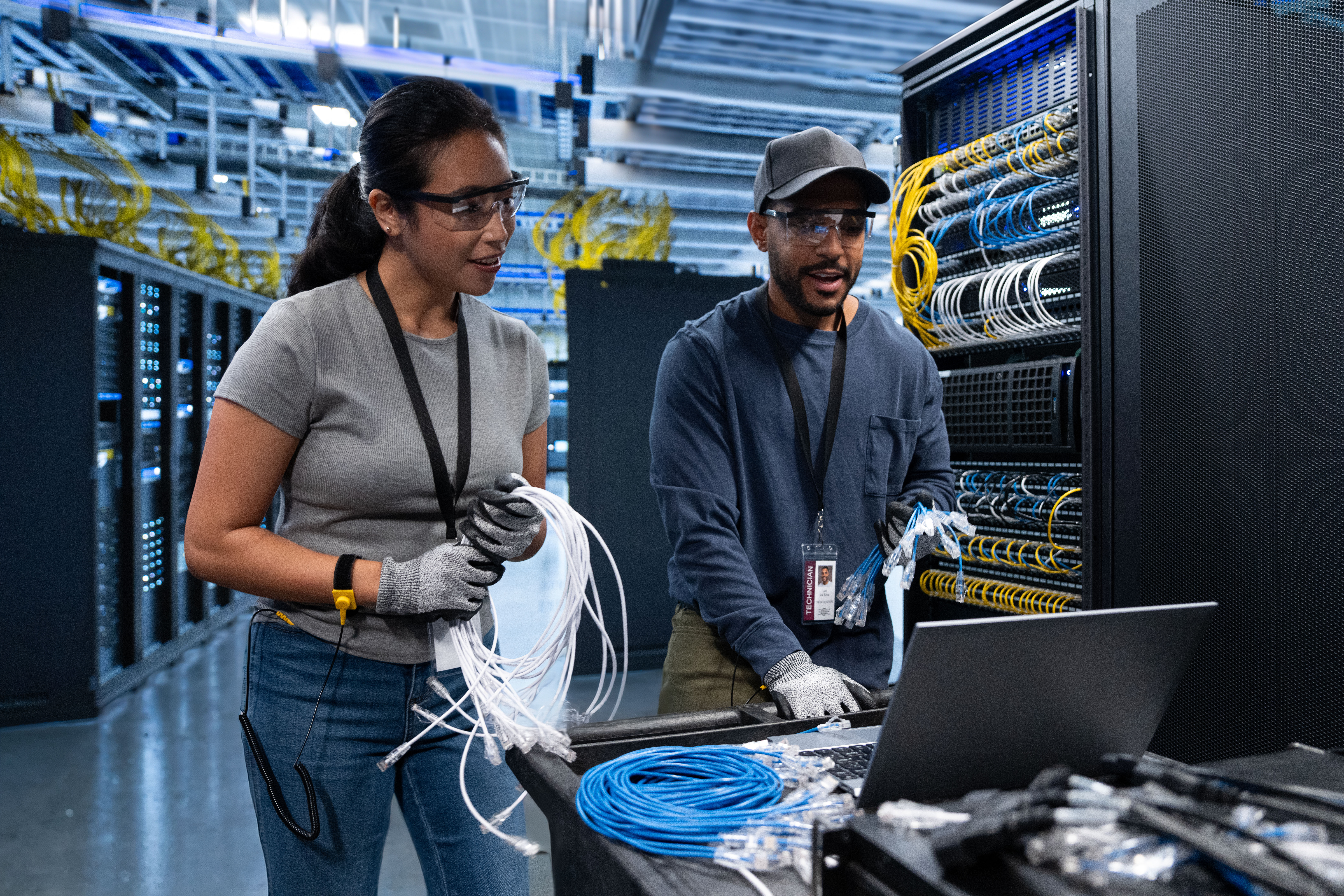 Two Low Voltage Technicians working on Cable at a laptop in a Data Center server room