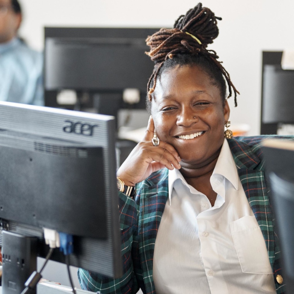 Tech women of color at a desk smiling